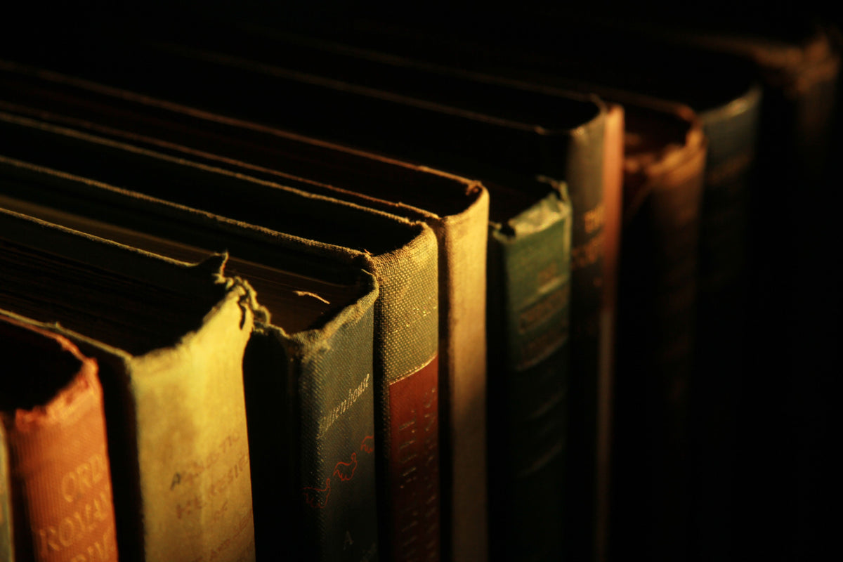 Antique leatherbound books with worn spines and ornate gilt tooling.
